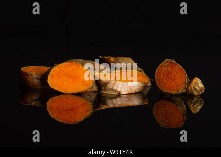 Sacco di fette di luminoso fresco curcuma rizoma isolato sul vetro nero Foto Stock
