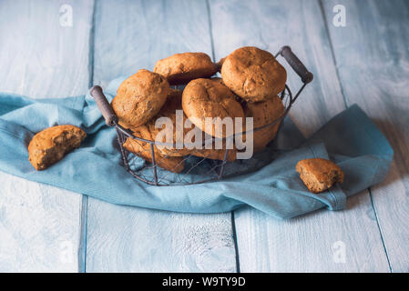 Tavolo per la colazione con pane di segale panini in un vintage cestello di ferro su un blu asciugamano da cucina. Il pane fatto in casa panini con segale e dadi. Appena sfornato ciambelle calde. Foto Stock