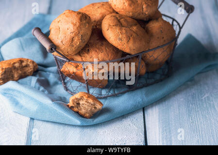 Panini caldi in un rustico cestello di ferro, home-cotta con farina di segale e nocciole, su un blu asciugamano da cucina. Gustosa colazione panini. Mangiare sano. Foto Stock