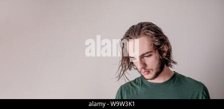 Giovane ragazzo guardando giù, giovane ragazzo o uomo, Foto ritratto di capelli bagnati modello con isolato la zona vuota Foto Stock