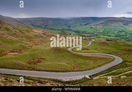 Uno stretto vicolo del paese si snoda attraverso la brughiera a Mam Tor nel Derbyshire Peak District, con Edale e la Kinder Scout colline dietro. Foto Stock