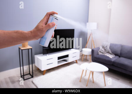 Close-up di mano di una persona spruzzare aria rinfrescante nel soggiorno Foto Stock