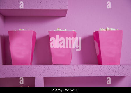 Un ampio box classico del teatro di popcorn isolati su rosa . Il Popcorn rovesciato da una scatola con striping . Tre vintage-style di scatole di popcorn in un tema di carnevale Foto Stock