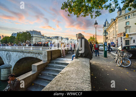 Turisti e locali parigini di raccogliere al crepuscolo presso il Pont Saint-Michel lungo le rive del fiume Senna sull'Ile de la Cite a Parigi Francia. Foto Stock