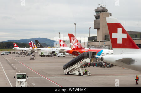 Gli aerei il rifornimento di carburante e il caricamento all'aeroporto di Zurigo, Svizzera, con aria Maltese, Swiss Air e Star Alliance aeroplani su un cielo coperto eveni invernale Foto Stock