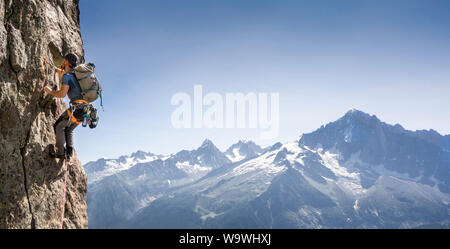 Giovane uomo rock climbing in Chamonix sul Clocher Clochetons attraversare sul Brévent davanti a una vista di Mont Blanc. Le Aiguilles Rouges, sulle alpi francesi. Foto Stock