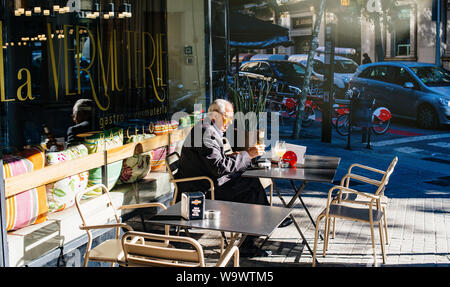 Barcellona, Spagna - 14 Nov 2017: vista laterale del senior singolo uomo di bere una birra presso la terrazza esterna nel centro di Barcellona La Vermouterie pub Foto Stock