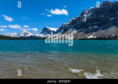 Bow Lake - una soleggiata giornata di primavera vista del cristallino e colorata al Lago Bow, circondata da cime innevate alte cime, presso il Parco Nazionale di Banff, AB, Canada. Foto Stock