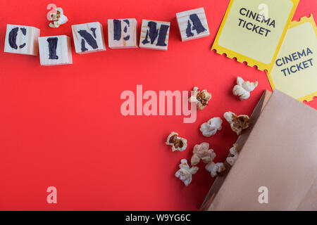 Borsa artigianale con pop-corn giallo due biglietti del cinema puzzle cubi di legno con testo cinema sfondo rosso Foto Stock