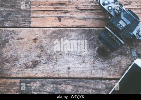 Foto a soffitto di una fotocamera e di uno smartphone su sfondo di legno marrone Foto Stock