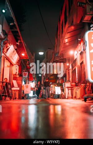 Foto di persone che camminano lungo una strada stretta vicino ai caffè E negozi durante la notte in Giappone Foto Stock