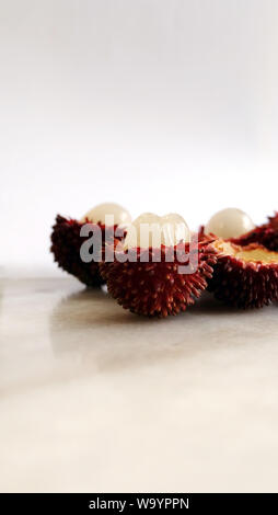 Sbucciate pulasan frutti nella foto verticale. Nome scientifico Nephelium ramboutan-akea, pulasan è un rosso di frutta tropicale che è strettamente alleati di rambutan. Foto Stock