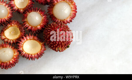 Vista superiore della frutta pulasan nell'angolo in alto a sinistra. Nome scientifico Nephelium ramboutan-akea, pulasan è un rosso di frutta tropicale strettamente alleati di rambutan. Foto Stock