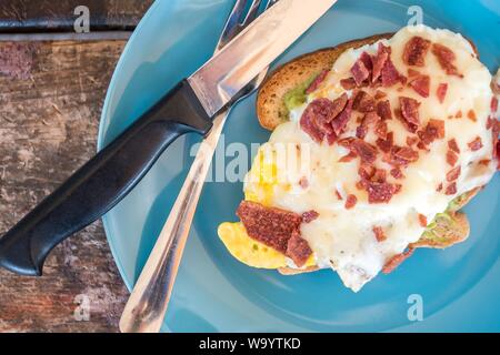 Un primo piano colpo di un gustoso sandwich di uova con salsiccia tagliata su una piastra di colore blu Foto Stock