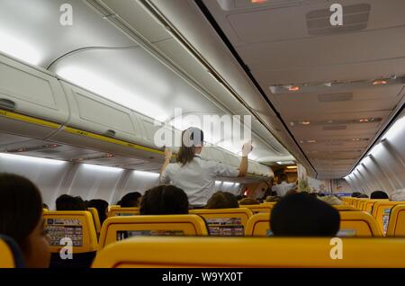 Interno di un volo Ryanair con equipaggio di cabina dando dimostrazione di sicurezza Foto Stock