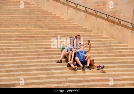 Famiglia pongono per selfie vicino al cancello principale di la Valletta malta sui gradini di pietra Foto Stock