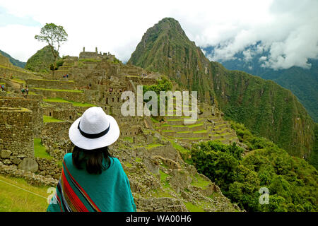 Visitatore femmina essendo impressionato con il sorprendente Machu Picchu cittadella Inca, Urubamba Provincia, Regione di Cusco, Perù Foto Stock