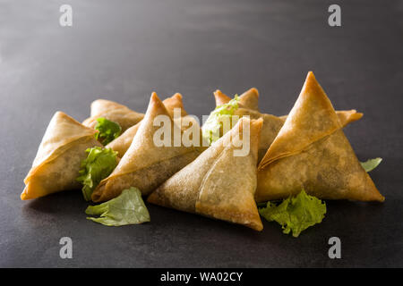 Samsa o samosas con carne e verdure su sfondo nero. Tradizionale cibo indiano. Foto Stock