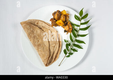 Chapati indiano e il pollo al curry in una piastra bianca Foto Stock