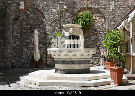 Acqua potabile fontana in marmo con teste di leone su una piazza nel centro storico di Porto Venere, liguria, Italia Foto Stock