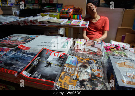 Hong Kong Cina. 16 Ago, 2019. Le riviste volte e The Economist hanno il conflitto in Hong Kong sul coperchio di una banchina edicola. Il venditore può accogliere in background. In Hong Kong vi sono state massicce proteste per più di due mesi. Le dimostrazioni sono state innescate da un disegno di legge del governo - ora in attesa - per l'estradizione di sospetti criminali in Cina. Credito: Gregor Fischer/dpa/Alamy Live News Foto Stock