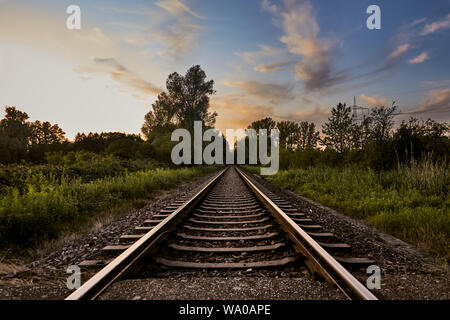 I binari della ferrovia infront di natura e il tramonto in Rastatt, Germania Foto Stock