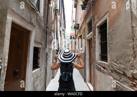 Vista posteriore delle donne a piedi attraverso uno stretto vicolo nel centro della città di Venezia Foto Stock