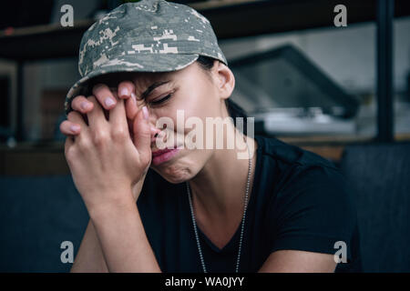 Premuto donna in uniforme militare con rinserrata mani piangendo a casa Foto Stock