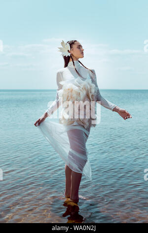 Sognante e donna elegante in White Swan costume in piedi sul fiume backgrond Foto Stock