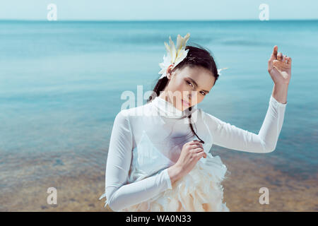 Brunette woman in White Swan costume in piedi vicino all'acqua, guardando la fotocamera Foto Stock