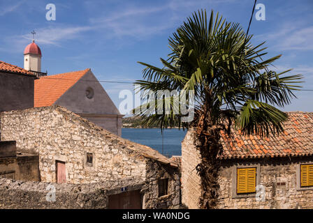 Piccola chiesa su di una collina tra le vecchie case di pietra. Orange tegole sul tetto e una piccola cupola di colore rosso sulla torre. Cielo blu con nuvole di luce. Sibenik, croato Foto Stock