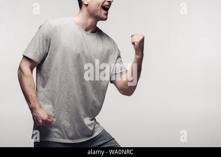 Uomo eccitato che mostra vincitore gesto isolato sul grigio, emozioni umane e concetto di espressione Foto Stock