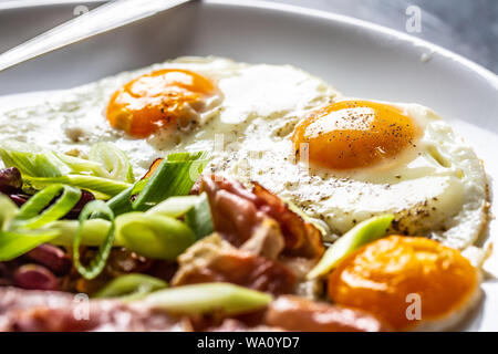 Prima colazione Inglese con uova, pancetta, fagioli e cipolle iyoung nella piastra bianca Foto Stock