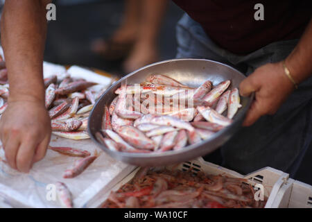 Il venditore mette una raffinata delicatezza i pesci per il compratore nel mercato del pesce Foto Stock