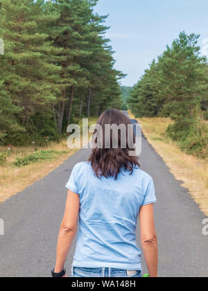 Vista posteriore di una donna in jeans camminando sulla strada Foto Stock