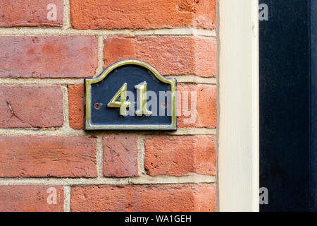 Il numero civico 41 su un metallo di colore nero sul segno rosso di un muro di mattoni Foto Stock