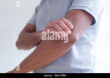 Uomo di toccare il suo gomito nel dolore. Foto Stock