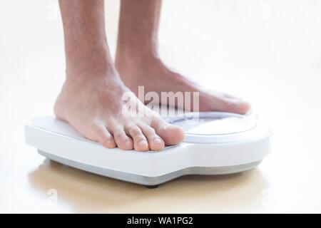 Uomo in piedi su una bilancia. Foto Stock