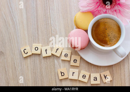 Buon pomeriggio messaggio pausa caffè concetto tazza bianca di spuma di caffè espresso con colorate amaretti francese su sfondo di legno, lo spazio per il testo. Foto Stock