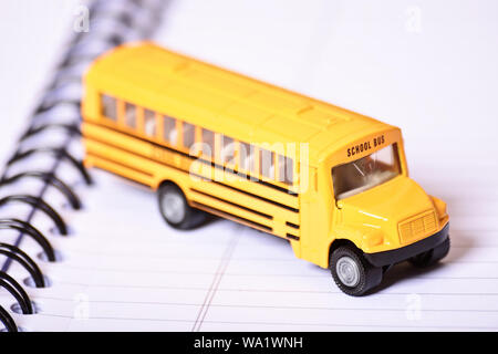 Immagine ravvicinata di un giocattolo di scuola bus sulla parte superiore di una spirale aperta notebook. Foto Stock