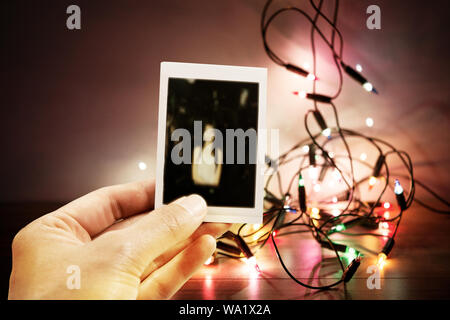 Retro Vintage Tone foto, mano azienda Instant foto sfocata con sfocate Luci di Natale sfondo. Foto Stock