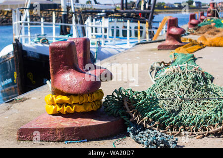 Una ghisa bollard ormeggio e reti da pesca sulla banchina al Porto di Ardglass Irlanda del Nord Foto Stock