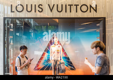 Bangkok, Tailandia - 19 Maggio 2019: una Louis Vuitton la finestra di visualizzazione a un negozio con due passanti in Siam Paragon Shopping Mall. Foto Stock