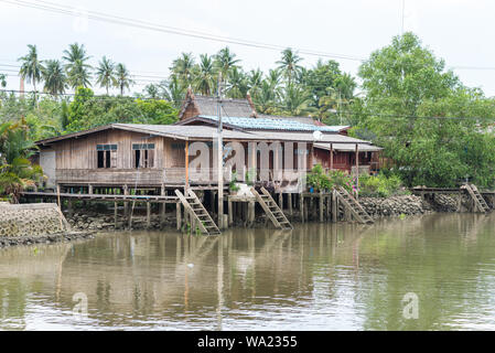 Legno Casa Stilt accanto a un canale in Samut Songkhram provincia, Thailandia. In corrispondenza di una gita in barca da mercato galleggiante di Amphawa. Foto Stock
