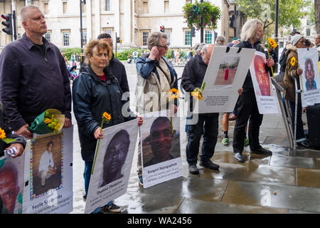 Londra, Regno Unito. 16 ago 2019. Gli attivisti con fiori e fotografie della miniera assassinati lavoratori durante la veglia in Sud Africa House in Trafalgar Square e sul settimo anniversario della deliberatamente programmato massacro di 34 colpisce i minatori a Lonmin Marikana della miniera di platino dalla polizia sudafricana per Londra mining company Lonmin, i cui direttori inclusi Cyril Ramaphosa, ora Presidente del Sud Africa. Nessuno è stato sottoposto a procedimento penale per gli omicidi e che chiamano per la giustizia e per la compensazione per le famiglie dei lavoratori. Credito: Peter Marshall / Alamy Live News Foto Stock