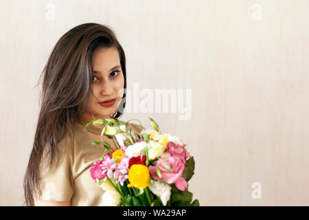 Bellissimo centro-est della ragazza con un mazzo di fiori. Giovane donna attraente con fiori. Ritratto di una cittadina graziosa ragazza Foto Stock