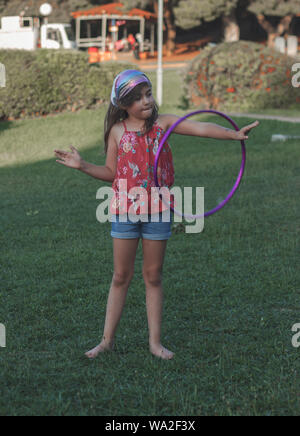 Bambina sta giocando con il suo hula hoop nel parco Foto Stock