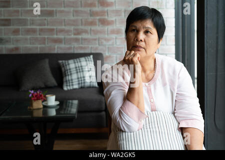 Senior asia donna pensare e guardare di traverso, pensare e chiedersi Foto Stock