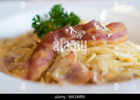 Close up. Freschi e deliziosi spaghetti alla carbonara con pancetta affumicata, immersione sul piatto bianco, nel ristorante di lusso, pizza italiana il concetto di cibo. Foto Stock