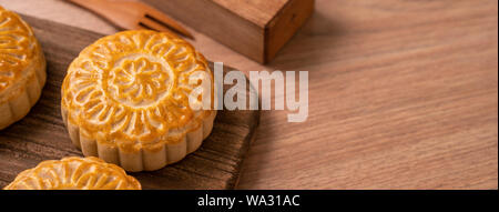 Una forma rotonda sfornato fresco torta della luna - pasticceria Cinese per moonckae Mid-Autumn Festival di luna su sfondo di legno e serve il vassoio, close up, spazio di copia Foto Stock